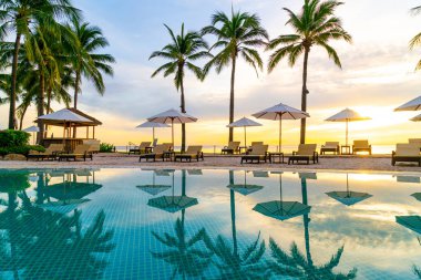 Şemsiye ve sandalye oteldeki yüzme havuzunda sabah gün doğumuyla birlikte - tatil ve tatil konsepti