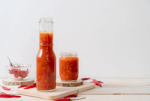chilli or chilli sauce in bottle and jar on wwod background