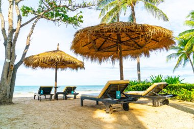 Plaj sandalyesi ve şemsiyesi okyanus sahili arka planında.