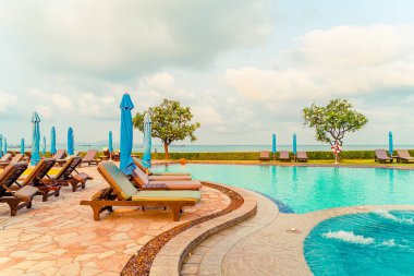 Tayland 'da Pattaya' da deniz plajı geçmişi olan havuz etrafında havuz ve şemsiye.