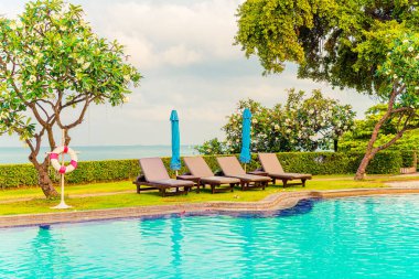 Sandalye havuzu ve şemsiyeyle okyanus arka planında yüzme havuzu