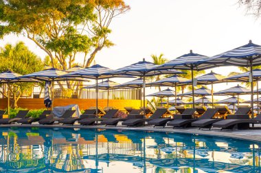 Seyahat tatili konsepti için otel otelinde yüzme havuzunun etrafında şemsiye ve havuz yatağı.