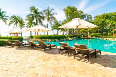 Otelde ve tatil beldesinde yüzme havuzunda güzel şemsiye ve sandalye - tatil kavramı