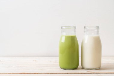 Ahşap arka planda taze sütle kibrit yeşil çay.