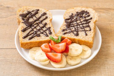 Kahvaltıda taze muz, çilek ve çikolatalı tam buğday ekmeği.