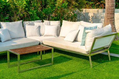 Bahçe sandalyesinde rahat yastıklar ve bahçede masa.