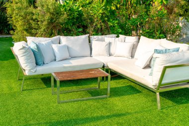 Bahçe sandalyesinde rahat yastıklar ve bahçede masa.