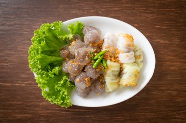 Şeffaf toplara Saku Sai Moo ya da Buharlı Tapioca Köfte Topları ve (Kow Griep Pag Mor) Domuz Buharlı Pirinç Paketleri ya da Haşlanmış Pirinç Kabuklu Mantı denir.