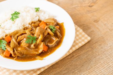 Dilimlenmiş domuz eti, havuç ve soğanlı Japon körili pilavı. Asya usulü.