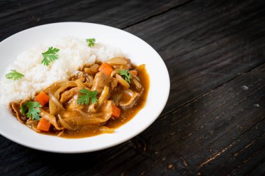 Dilimlenmiş domuz eti, havuç ve soğanlı Japon körili pilavı. Asya usulü.