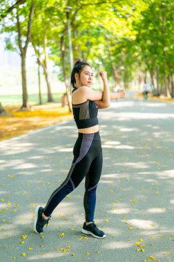 Parkta egzersiz yapmadan önce esneme hareketleri yapan Asyalı kadın.