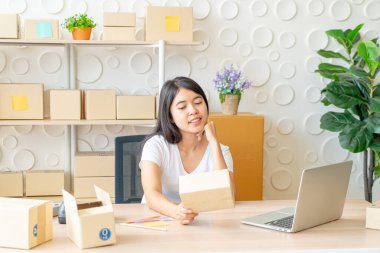 Asyalı bir kadın internette dizüstü bilgisayar ve ofis telefonlarını kullanırken eğleniyor - online veya çevrimiçi alışveriş kavramı satmak