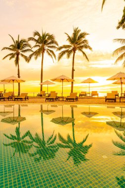 Şemsiye ve sandalye oteldeki yüzme havuzunda sabah gün doğumuyla birlikte - tatil ve tatil konsepti