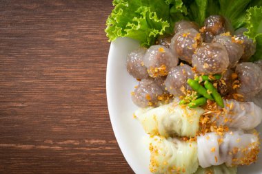 Şeffaf toplara Saku Sai Moo ya da Buharlı Tapioca Köfte Topları ve (Kow Griep Pag Mor) Domuz Buharlı Pirinç Paketleri ya da Haşlanmış Pirinç Kabuklu Mantı denir.