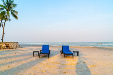 Sahilde deniz ve gökyüzü arka planlı boş bir plaj sandalyesi.