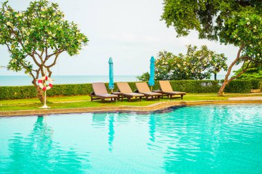 Sandalye havuzu ya da yüzme havuzu etrafında şemsiye olan yatak havuzu