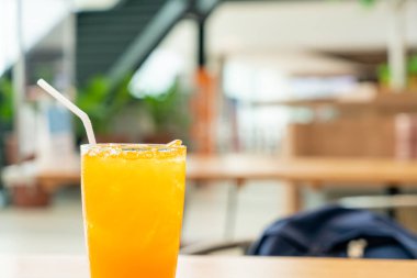 Kafe restoranındaki ahşap masada buzlu portakal suyu.