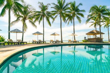 Otelde ve tatil beldesinde yüzme havuzunda güzel şemsiye ve sandalye - tatil kavramı