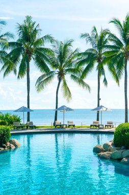 Otelde ve tatil beldesinde yüzme havuzunda güzel şemsiye ve sandalye - tatil kavramı