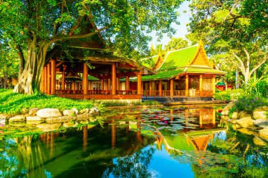 Bahçede ağaç ve göl olan Tayland tarzında bir pavyon.