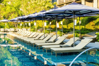 Seyahat tatili konsepti için otel otelinde yüzme havuzunun etrafında şemsiye ve havuz yatağı.