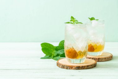Sodayla buzlu erik suyu ve ahşap masada nane şekeri - içecek.