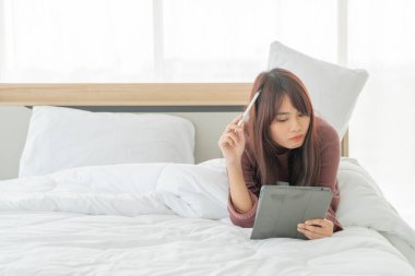 Yatakta tabletle çalışan güzel Asyalı kadınlar