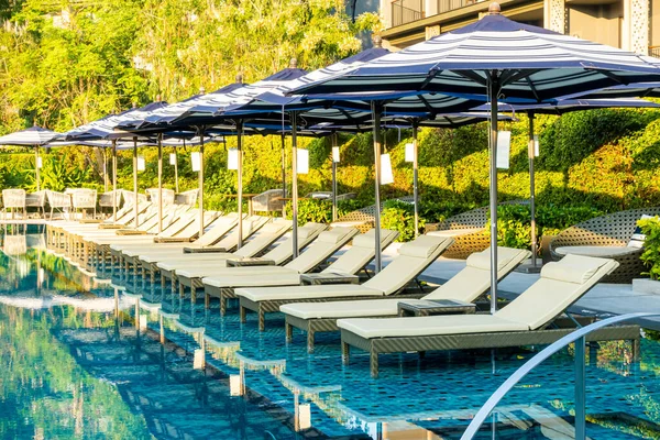 Seyahat tatili konsepti için otel otelinde yüzme havuzunun etrafında şemsiye ve havuz yatağı.