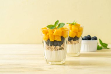 Ev yapımı taze mango ve yoğurt ve granola ile taze yaban mersini. Sağlıklı yemek tarzı.