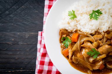 Dilimlenmiş domuz eti, havuç ve soğanlı Japon körili pilavı. Asya usulü.