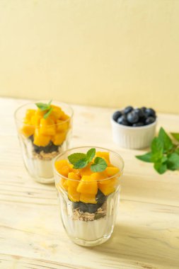 Ev yapımı taze mango ve yoğurt ve granola ile taze yaban mersini. Sağlıklı yemek tarzı.