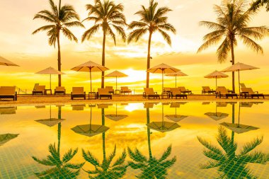 Şemsiye ve sandalye oteldeki yüzme havuzunda sabah gün doğumuyla birlikte - tatil ve tatil konsepti