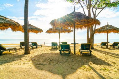 Şemsiye ve sahil sandalyesi Hindistan cevizi palmiyesi ve deniz plajı arka planı ve mavi gökyüzü - tatil ve tatil kavramı