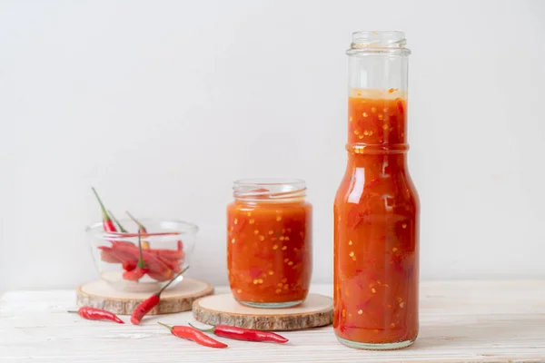 chilli or chilli sauce in bottle and jar on wwod background