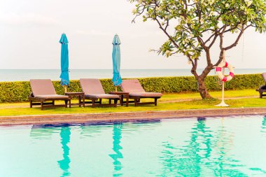 Sandalye havuzu ya da yüzme havuzu etrafında şemsiye olan yatak havuzu