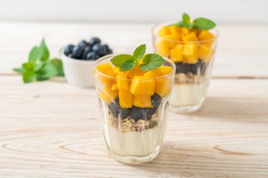 Ev yapımı taze mango ve yoğurt ve granola ile taze yaban mersini. Sağlıklı yemek tarzı.