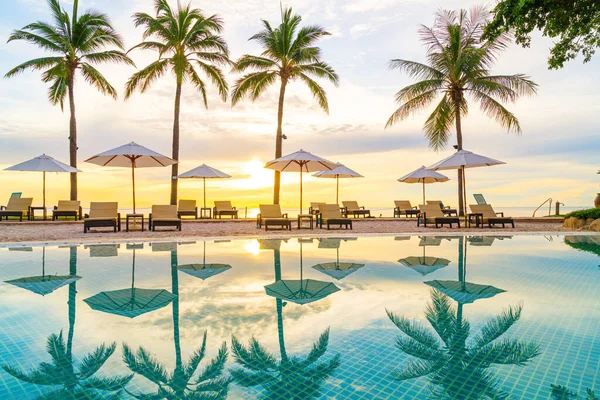 Şemsiye ve sandalye oteldeki yüzme havuzunda sabah gün doğumuyla birlikte - tatil ve tatil konsepti