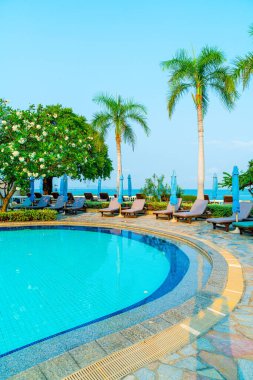 Hindistan cevizi palmiyeli havuz etrafında sandalye ve şemsiye - tatiller ve tatil kavramı