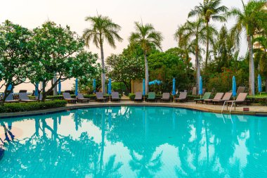 Gün batımında yüzme havuzunda şemsiyeli plaj sandalyesi ya da bilardo yatağı