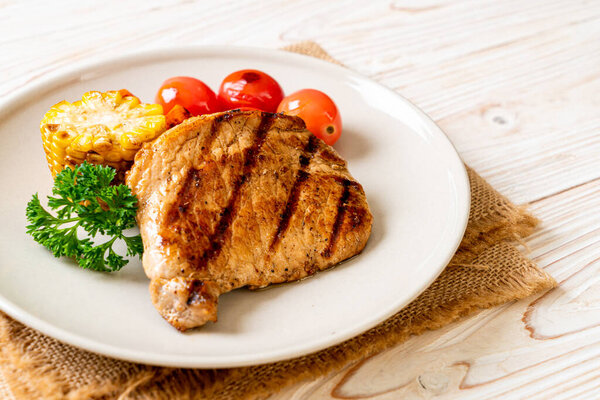 grilled and barbecue fillet pork steak with corn, carrot and tomatoes