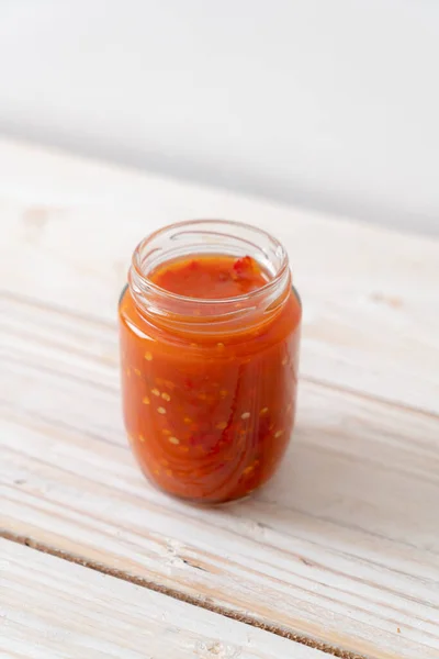 chilli or chilli sauce in bottle and jar on wwod background