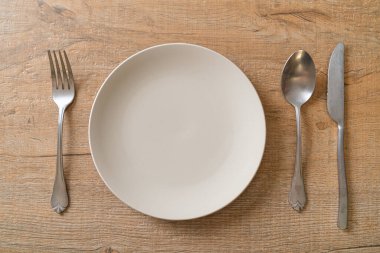 Ahşap zemin üzerinde bıçak, çatal ve kaşık olan boş tabak veya tabak