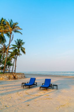 Sahilde deniz ve gökyüzü arka planlı boş bir plaj sandalyesi.