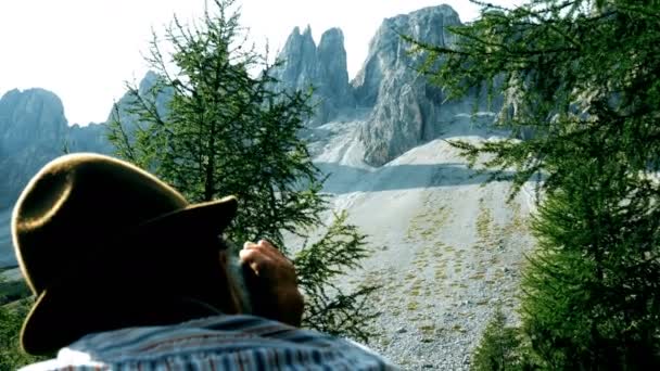 Homem idoso olha através dos binóculos para as montanhas — Vídeo de Stock