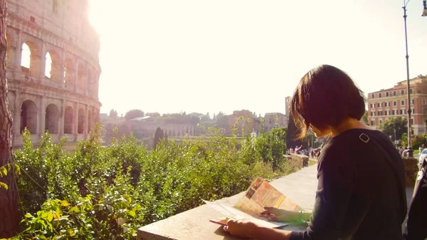 Женщина смотрит на туристическую карту перед величественным Колизеем в Риме — стоковое фото