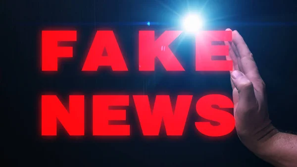 En mans hand kompresser, ordet falska nyheter — Stockfoto