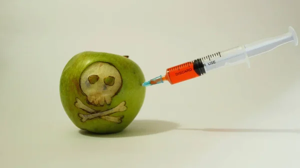 Şırınga oyulmuş bir kafatası, temsilcisi ile bir yeşil elma GDO maddelerin kullanımı görüntüsünü gıda, sebze ve meyve eklenen — Stok fotoğraf