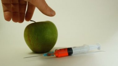 bir yeşil elma kazıma bir kanlı kafatası ve şırınga, GDO maddelerin gıda, sebze ve meyve kullanımı temsil edici bir görüntü ile bir el turnike
