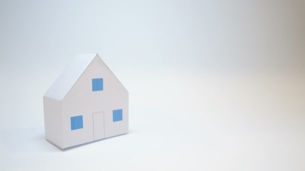 Бумажный дом, символизирующий семью, защищен руками страховщика от несчастного случая — стоковое видео