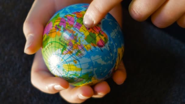 Una adolescente sostiene un mini globo en su mano, con su mano indica el camino de la inmigración de África a Europa, material adecuado para contar los fenómenos migratorios de una manera sencilla — Vídeos de Stock